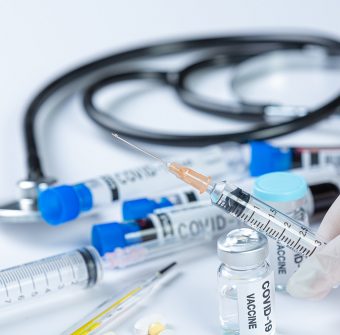 Close up a vial of covid-19 vaccine in hand of a scientist or doctor